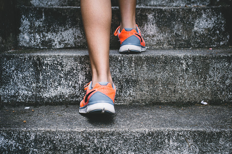 A woman's feet wearing tennis shoes climbing stairs.