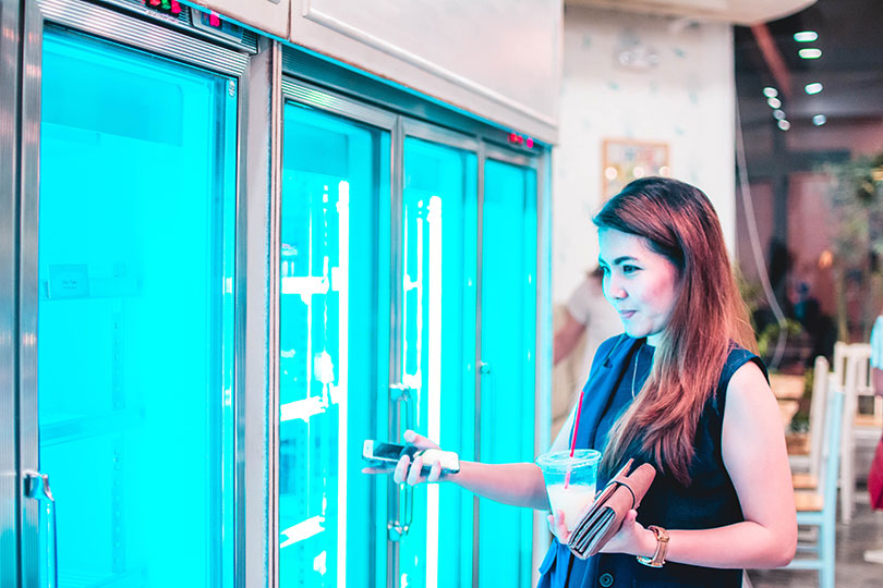 Woman looks inside cooler doors while shopping