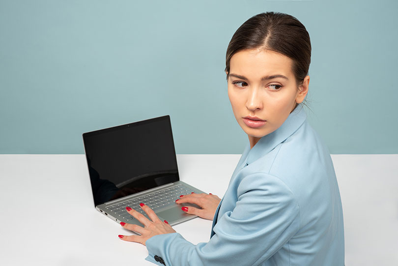 Woman looks over her shoulder while sitting in front of a laptop.