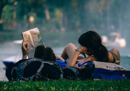 Young couple lying on grass looking a map.