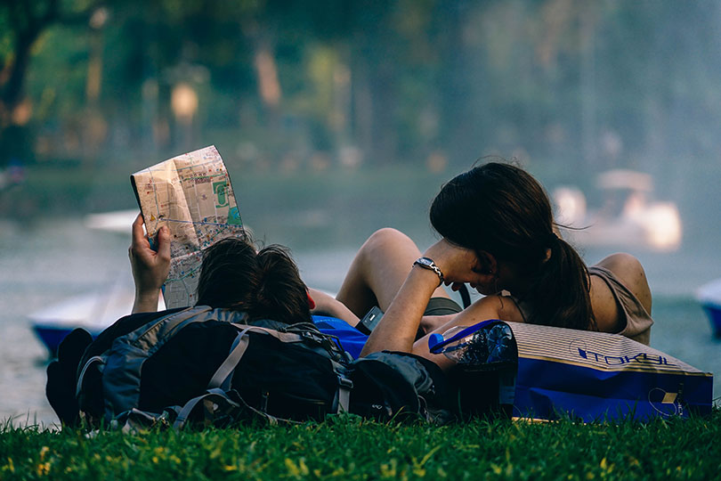 Young couple lying on grass looking a map.