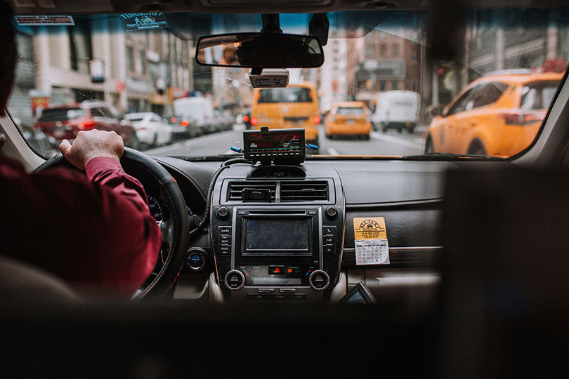 Driver sits behind the wheel of a car in city traffic.