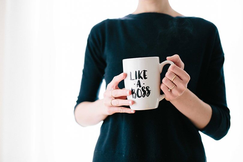 Torso of a woman holding a mug that reads like a boss