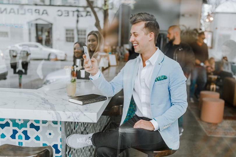 Man sitting at a counter, smiling while looking at a smartphone. 