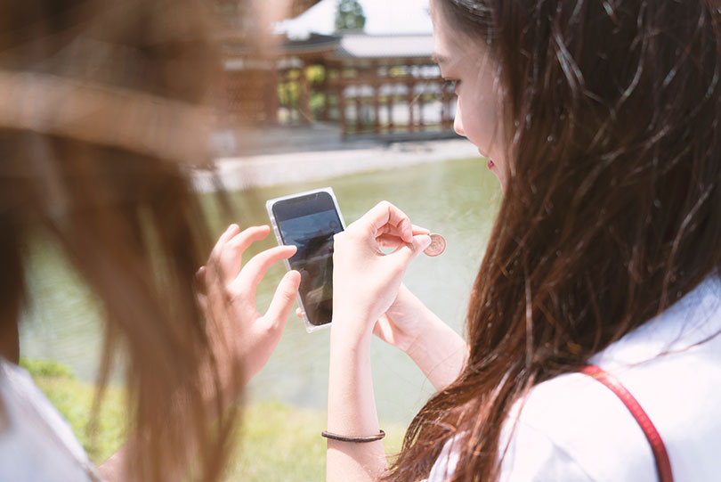 Young woman looks at image in phone. 