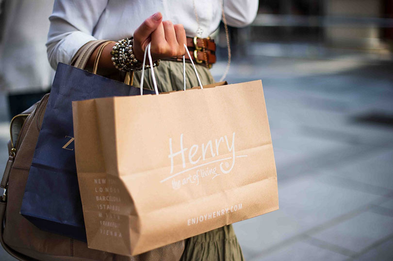 Woman’s arm shown carrying lots of department store bags.