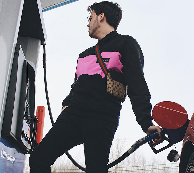 Man wearing Gucci fuels up his car at gas station.