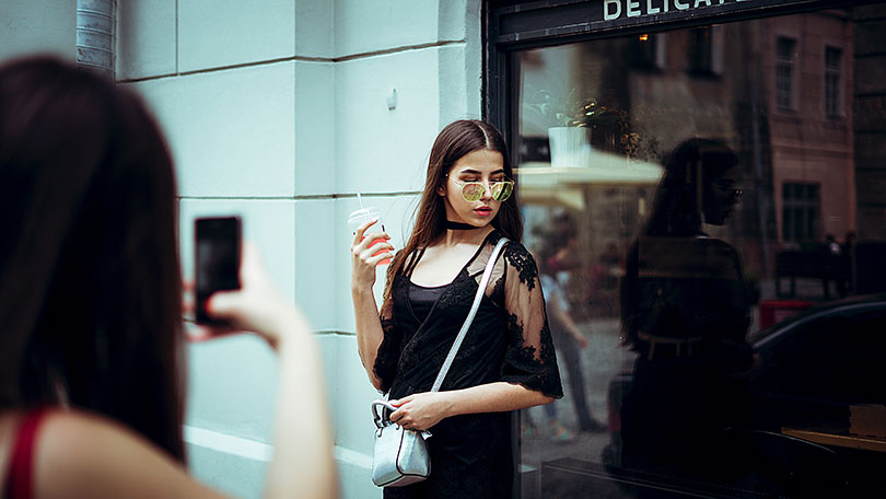 Woman takes a picture of another woman using a mobile phone. 