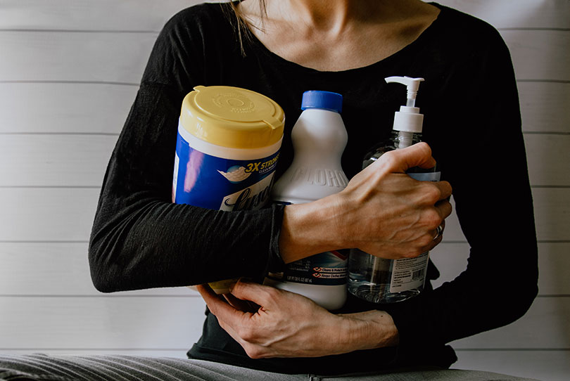 Woman holding cleaning supplies.