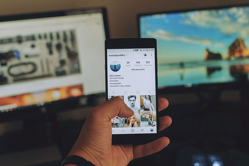 Man holds smartphone in hand with social media image on screen.