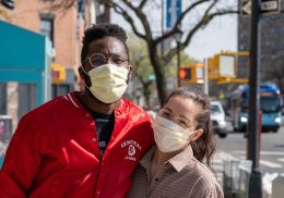 A couple wearing personal protection masks embrace in public