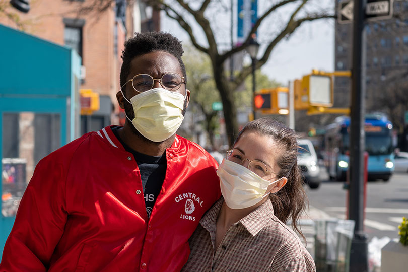A couple wearing personal protection masks embrace in public