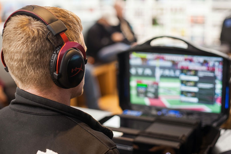 Man watching esports on a laptop and wearing headphones. 