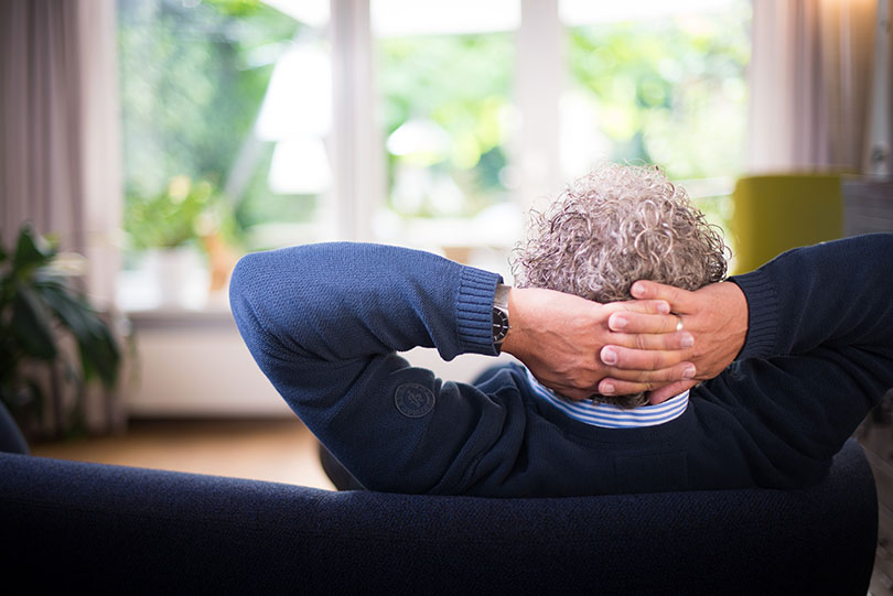 Middle aged man sitting on a couch, leaning back.