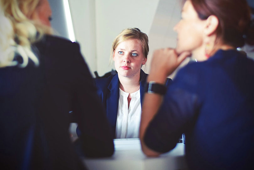 Woman sits across from two other women, listening