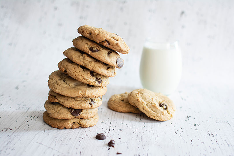 A stack of chocolate chip cookies and a glass of milk
