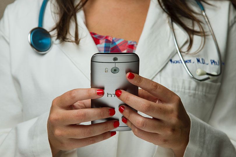 Doctor in lab coat holding a mobile phone. 