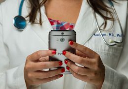 Doctor in lab coat holding a mobile phone.
