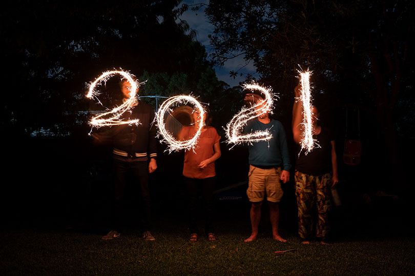 Four people write 2021 with sparklers