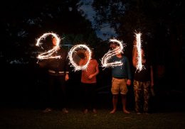 Four people write 2021 with sparklers