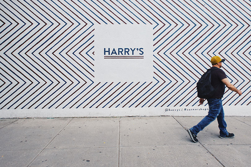 Man walking by a large poster advertising Harry’s.