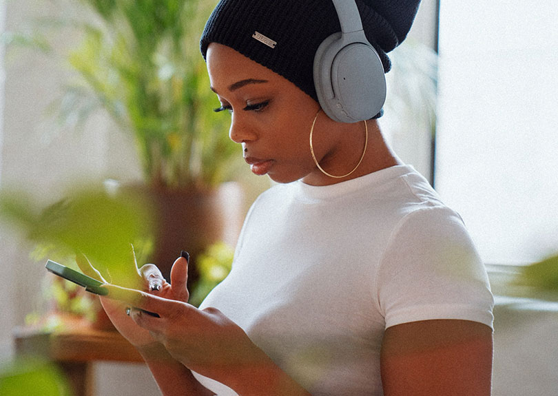 A woman wearing headphones while using a mobile phone