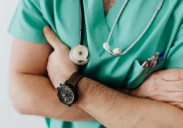 Close-up of medical provider in green scrubs with arms folded across chest.