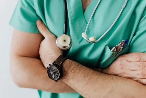 Close-up of medical provider in green scrubs with arms folded across chest.