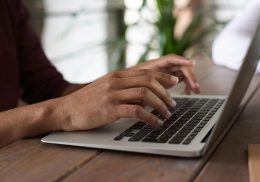 Close-up image of person typing on laptop.