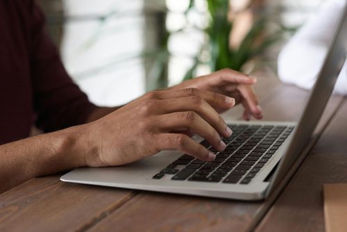 Close-up image of person typing on laptop.